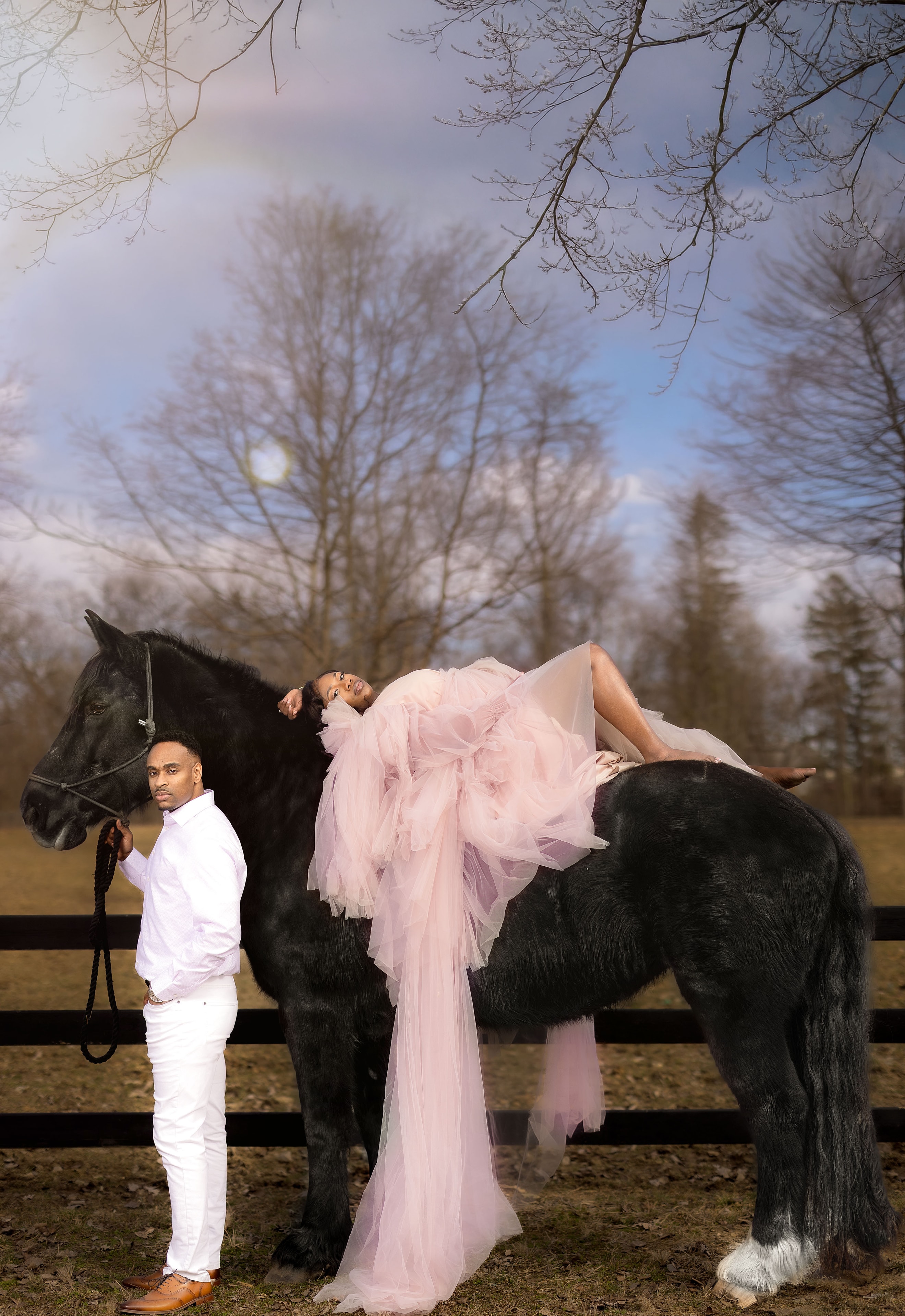 Couple posing on black horse outdoors
