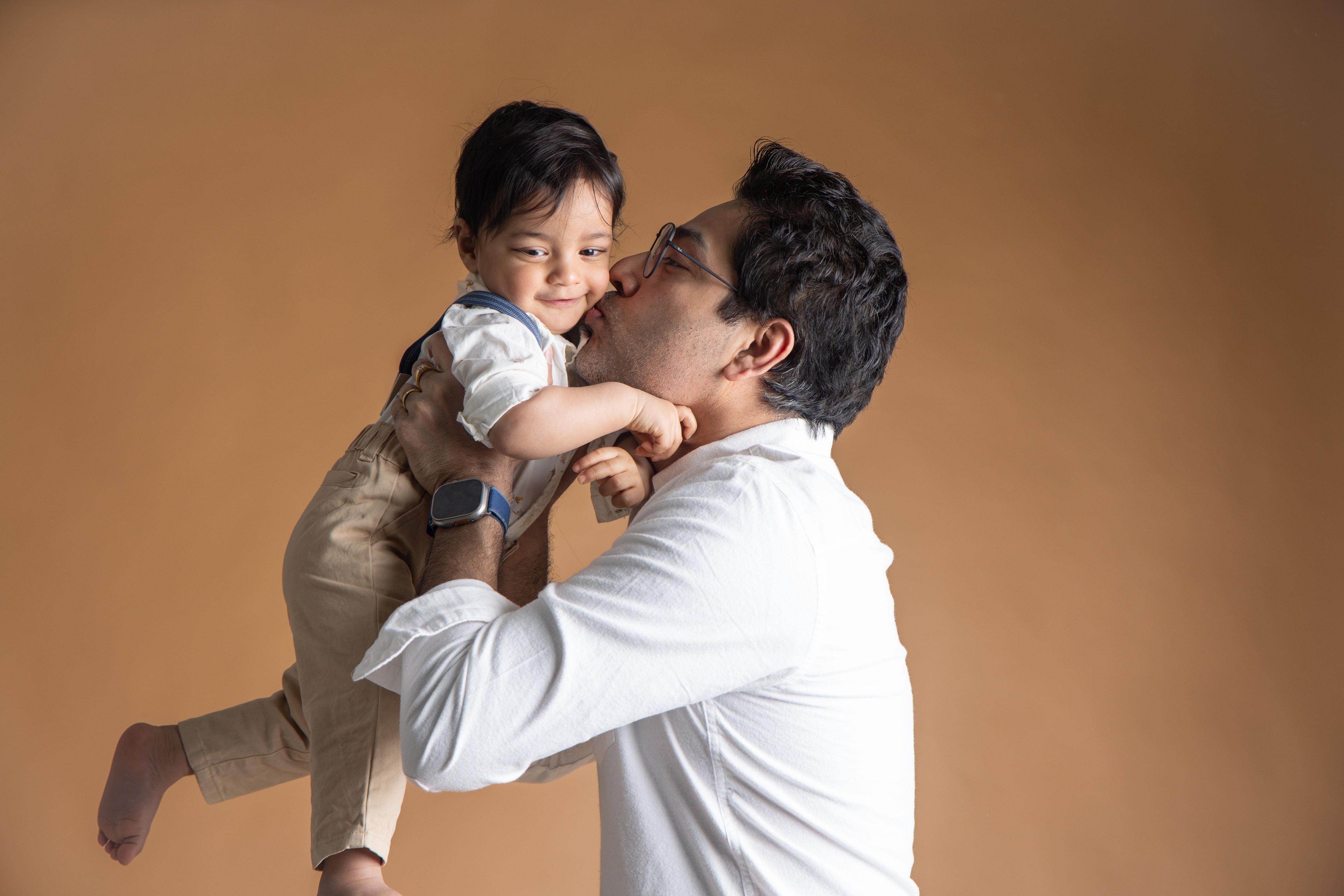 Father kissing toddler son playfully