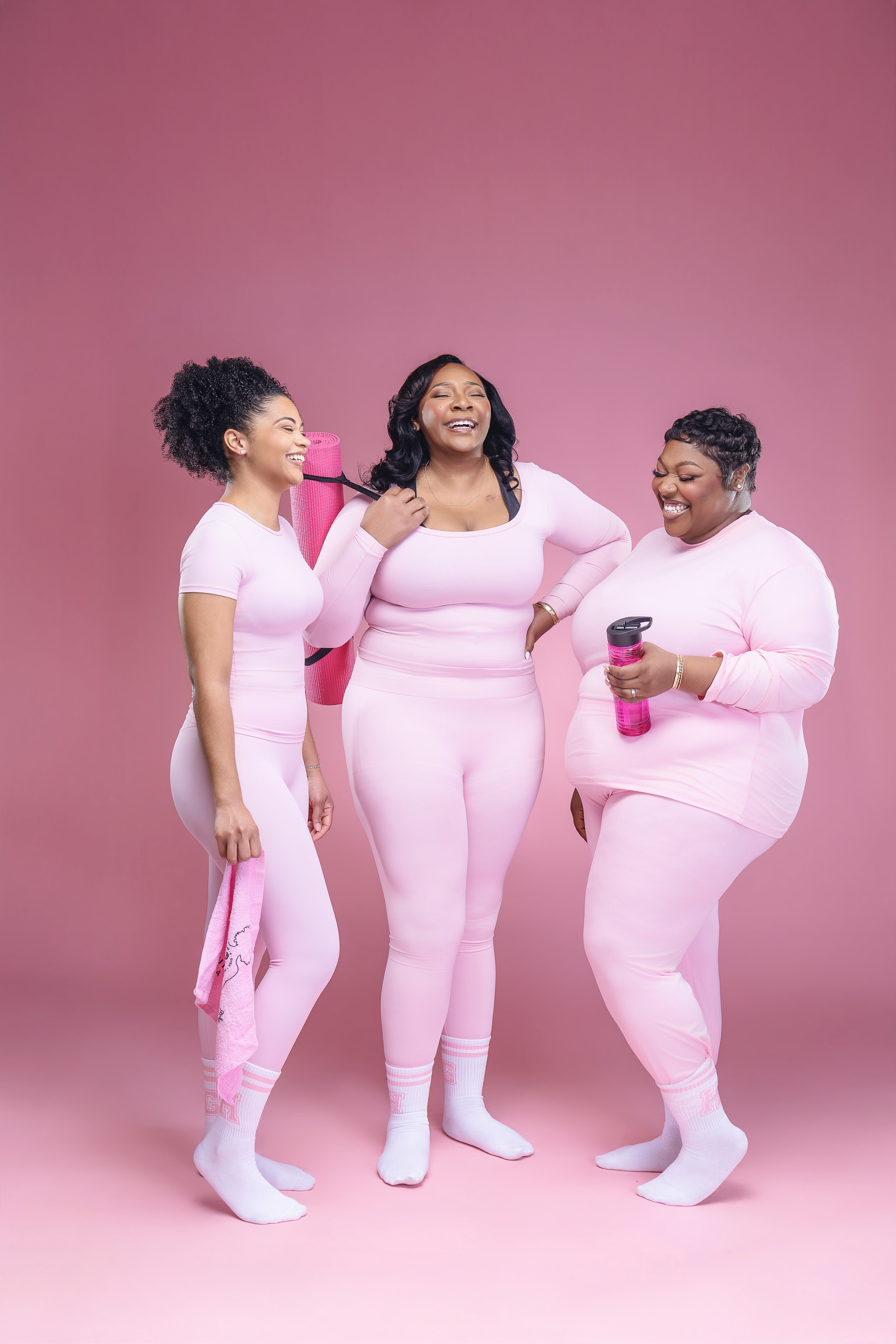 Three women in pink workout gear smiling